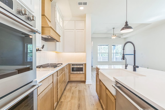 kitchen featuring white cabinetry, stainless steel appliances, light hardwood / wood-style flooring, tasteful backsplash, and pendant lighting