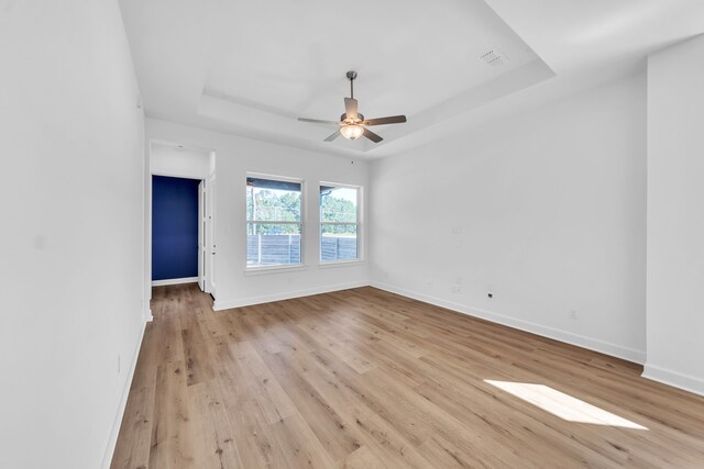 spare room featuring ceiling fan, light hardwood / wood-style flooring, and a tray ceiling