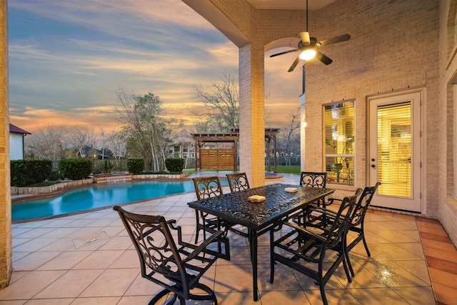 patio terrace at dusk with ceiling fan, a pergola, and a fenced in pool