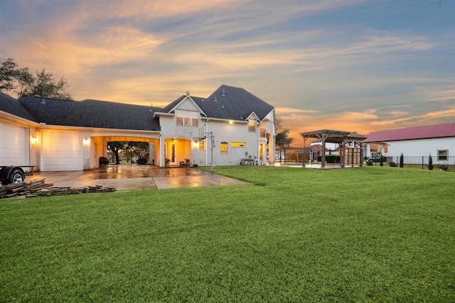 back house at dusk featuring a yard, a garage, and a pergola