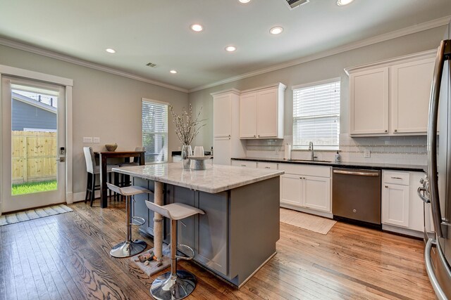 kitchen with white cabinets, light wood-type flooring, a kitchen island, and stainless steel appliances