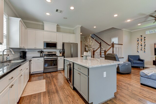 kitchen with open floor plan, appliances with stainless steel finishes, a sink, and white cabinetry