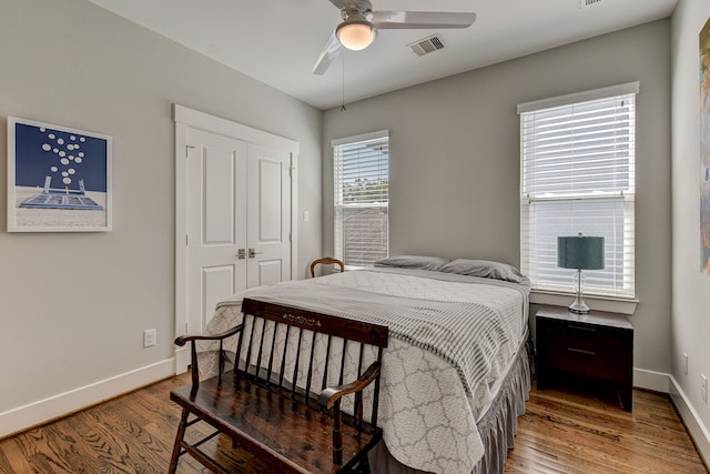 bedroom with a closet, visible vents, ceiling fan, wood finished floors, and baseboards