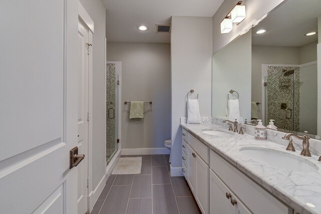 bathroom featuring double vanity, a shower stall, baseboards, and a sink