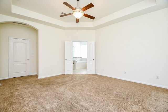 carpeted spare room featuring a tray ceiling and ceiling fan