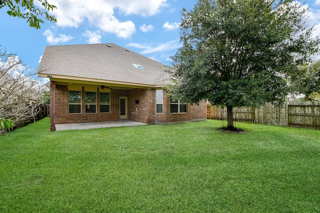 rear view of house featuring ceiling fan, a patio area, and a yard