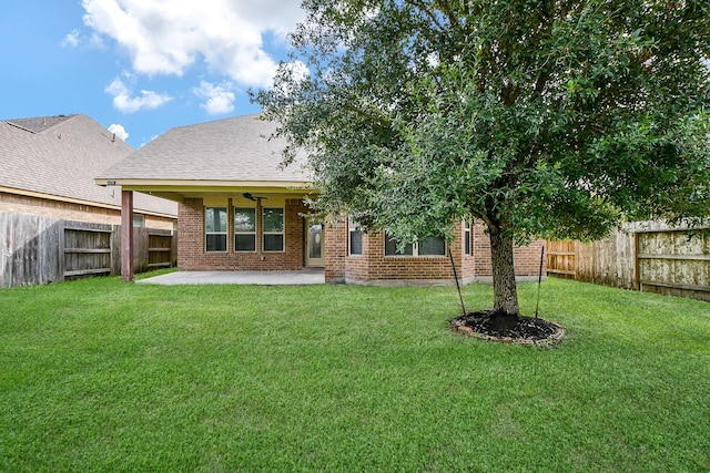 rear view of property featuring ceiling fan, a yard, and a patio