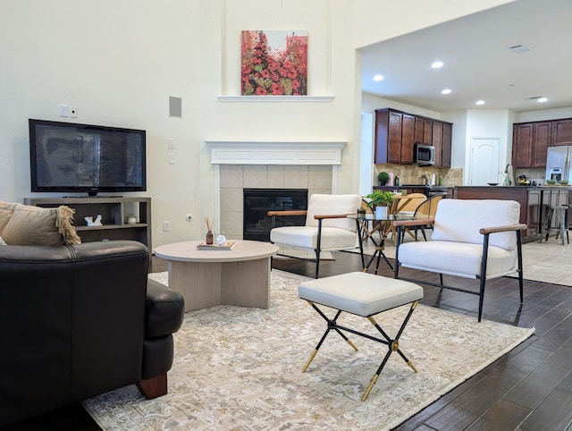 living room with wood-type flooring and a tiled fireplace