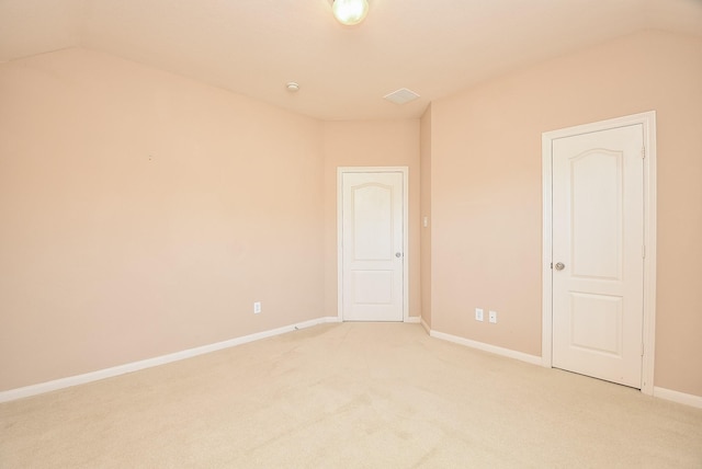 spare room featuring light colored carpet and vaulted ceiling