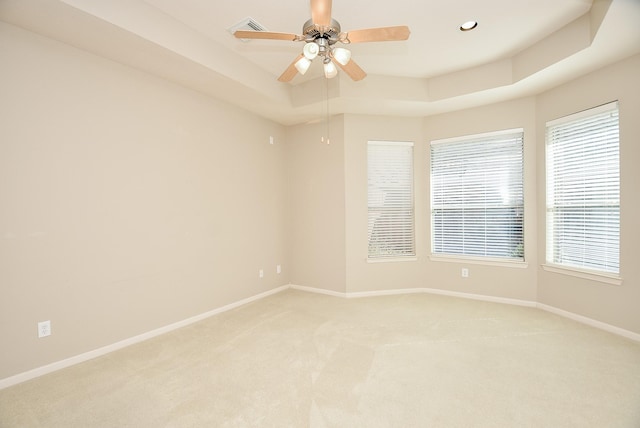 carpeted spare room featuring a tray ceiling and ceiling fan