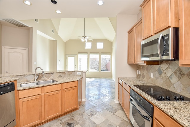 kitchen featuring light stone counters, sink, stainless steel appliances, and vaulted ceiling