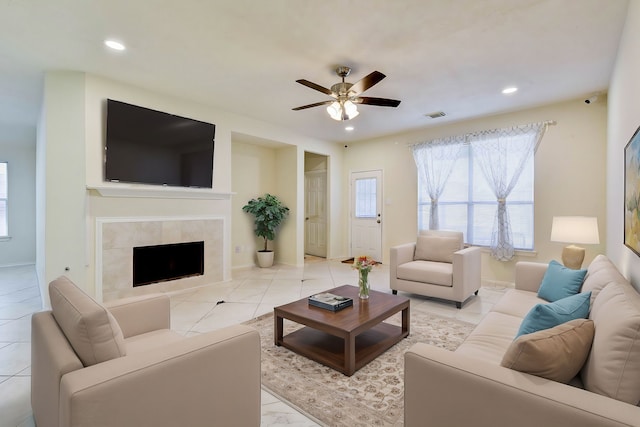 living room featuring a fireplace, ceiling fan, and light tile patterned flooring