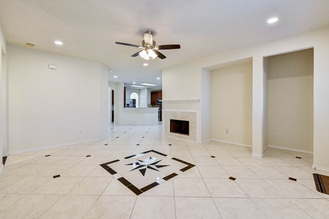 unfurnished living room featuring ceiling fan, light tile patterned floors, and a fireplace