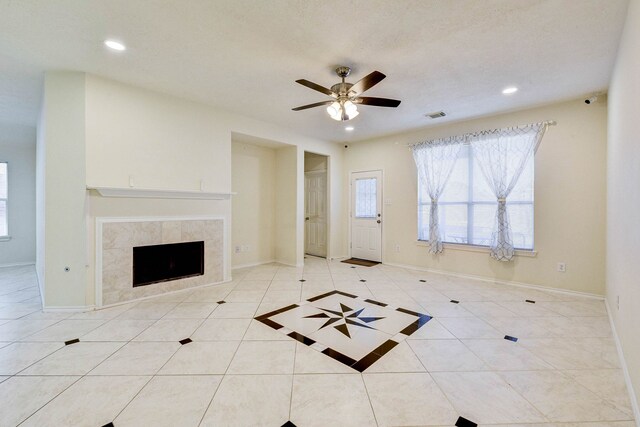 unfurnished living room featuring ceiling fan, light tile patterned floors, and a tile fireplace