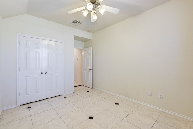 unfurnished bedroom featuring ceiling fan, a closet, light tile patterned floors, and vaulted ceiling