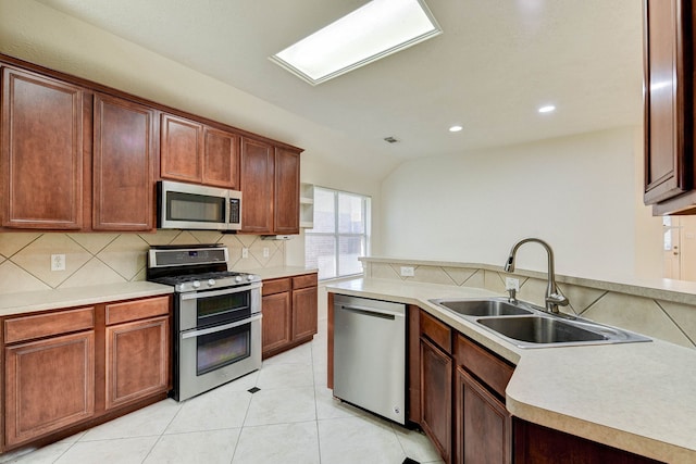 kitchen with lofted ceiling, backsplash, sink, appliances with stainless steel finishes, and light tile patterned flooring