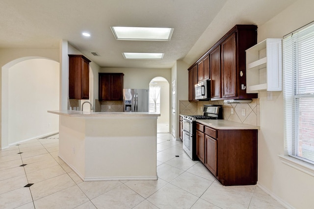 kitchen with sink, decorative backsplash, light tile patterned floors, appliances with stainless steel finishes, and dark brown cabinets