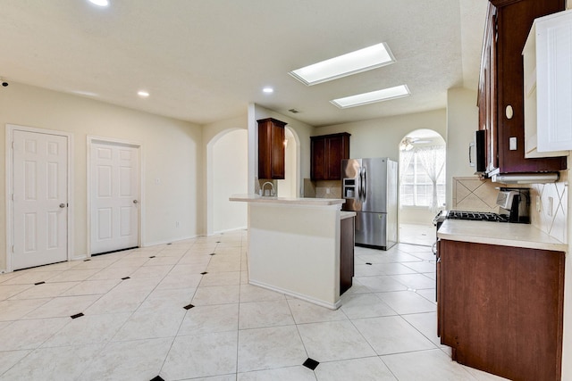 kitchen with ceiling fan, tasteful backsplash, stainless steel fridge, dark brown cabinets, and light tile patterned floors