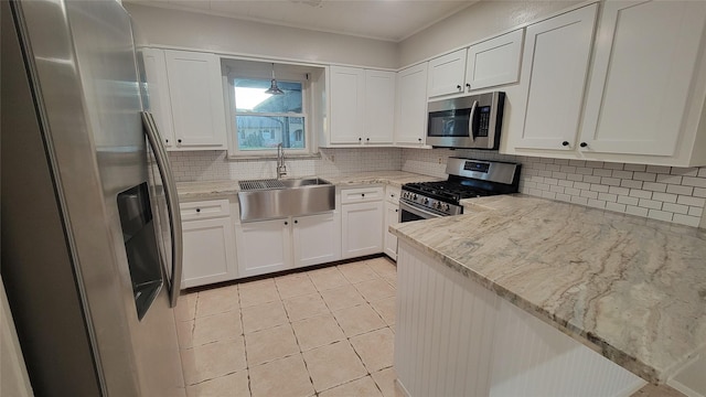 kitchen featuring sink, light tile patterned floors, light stone counters, white cabinets, and appliances with stainless steel finishes