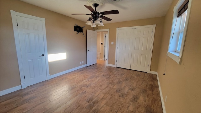 unfurnished bedroom with multiple windows, ceiling fan, and light hardwood / wood-style floors