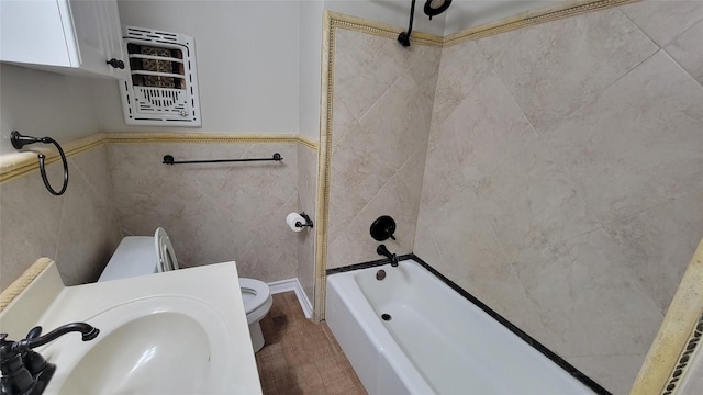 full bathroom featuring sink, heating unit, toilet, shower / bathing tub combination, and tile walls