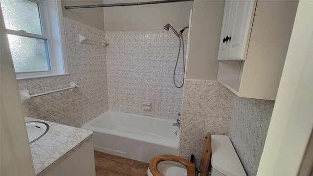 full bathroom featuring vanity, tiled shower / bath combo, toilet, and tile walls