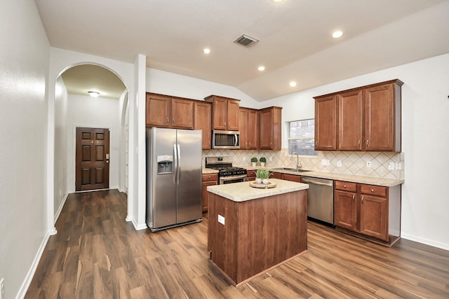 kitchen featuring sink, a center island, lofted ceiling, decorative backsplash, and appliances with stainless steel finishes