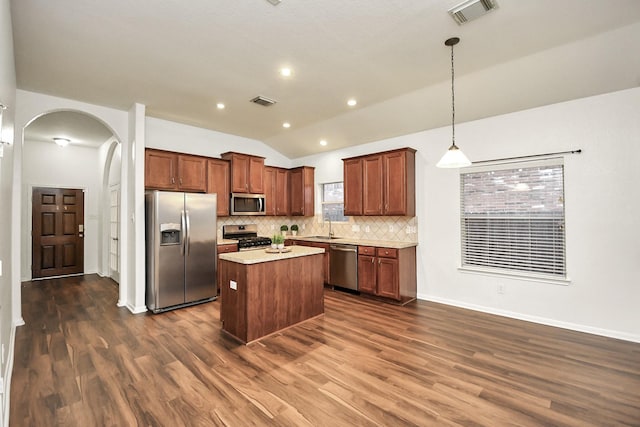 kitchen featuring sink, hanging light fixtures, stainless steel appliances, lofted ceiling, and a kitchen island