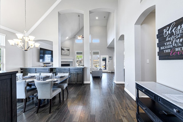 dining space featuring ceiling fan with notable chandelier, dark hardwood / wood-style floors, crown molding, and a high ceiling