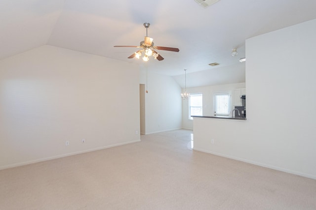 unfurnished room with ceiling fan with notable chandelier, light colored carpet, lofted ceiling, and sink