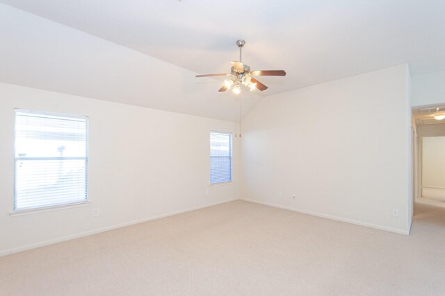 carpeted spare room with ceiling fan and vaulted ceiling