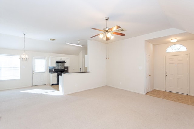 unfurnished living room featuring light carpet, ceiling fan with notable chandelier, and vaulted ceiling