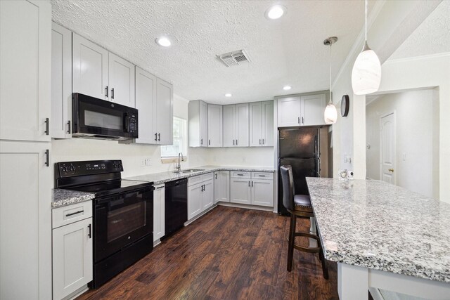 kitchen with pendant lighting, sink, a textured ceiling, and black appliances