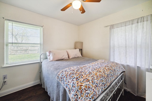 bedroom featuring ceiling fan, dark hardwood / wood-style flooring, and multiple windows