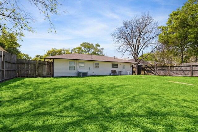 back of house featuring central air condition unit and a lawn