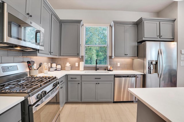 kitchen with decorative backsplash, gray cabinets, sink, and stainless steel appliances