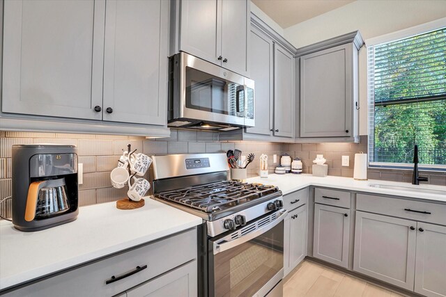 kitchen with backsplash, sink, gray cabinetry, and stainless steel appliances