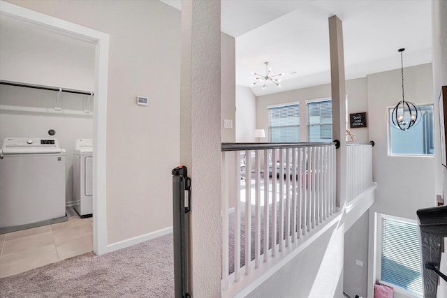 hall with washer and clothes dryer, light carpet, and a chandelier