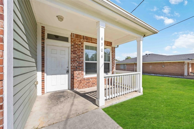 entrance to property featuring a porch and a yard