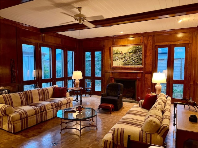 living room featuring beamed ceiling, ceiling fan, and wooden walls