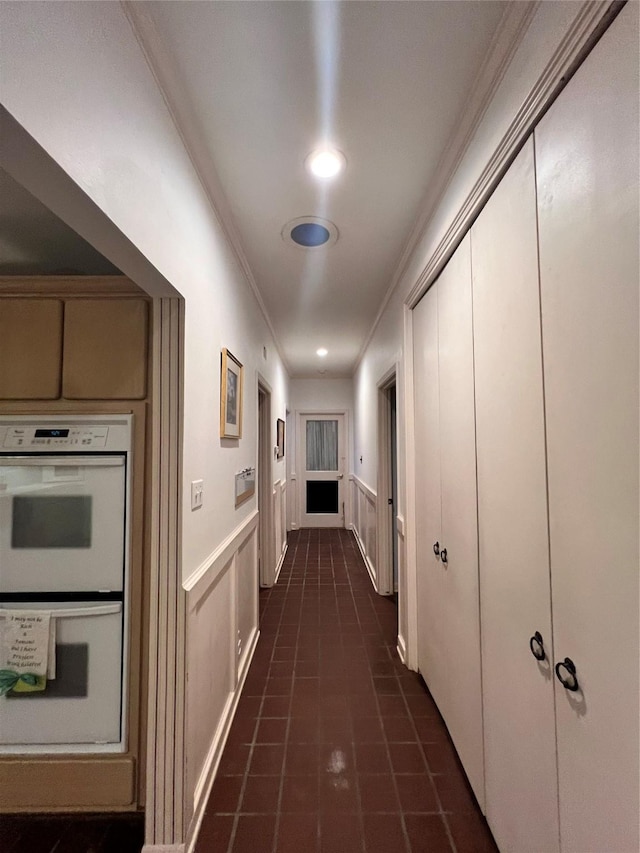 corridor with dark tile patterned floors and crown molding