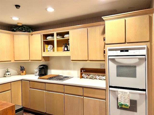 kitchen featuring gas cooktop, light brown cabinetry, and white double oven