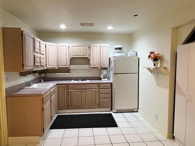 kitchen with light tile patterned flooring, light brown cabinets, white appliances, and sink