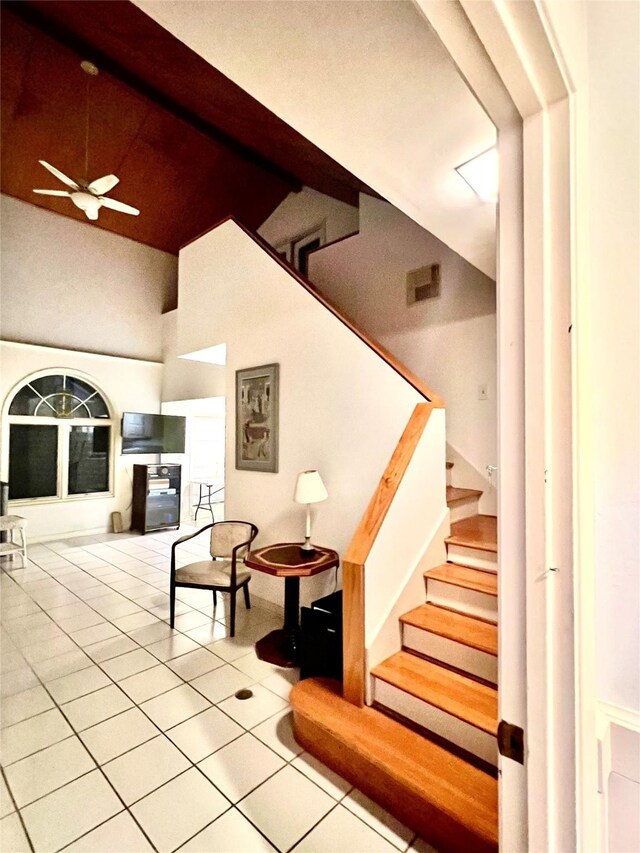 stairway with tile patterned floors, ceiling fan, and high vaulted ceiling