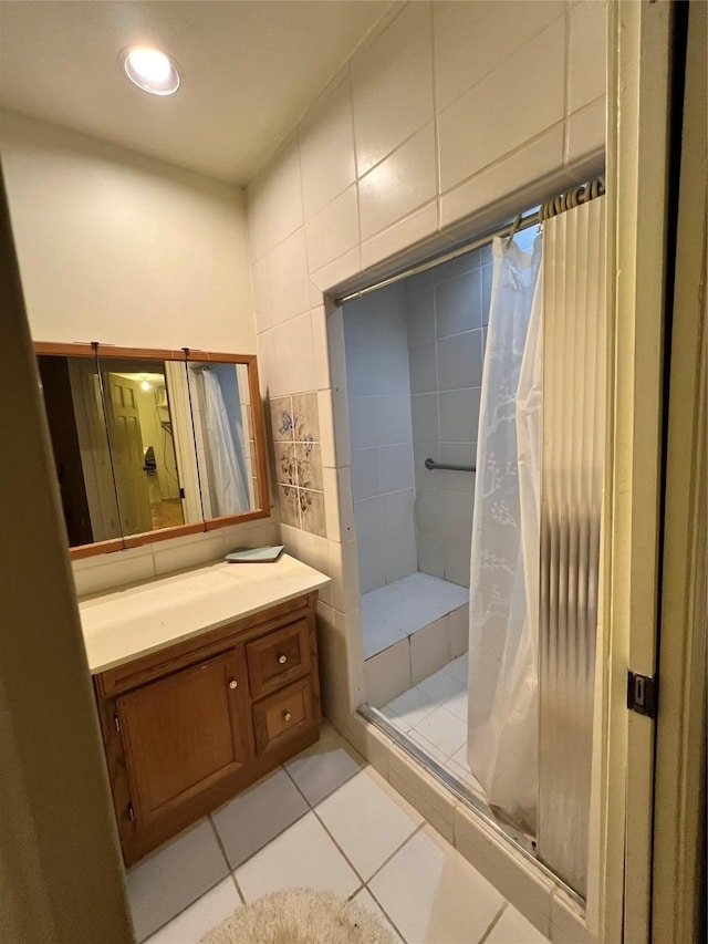 bathroom with a tile shower, tile patterned flooring, and vanity