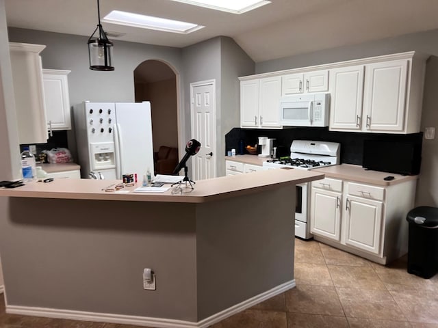 kitchen featuring white appliances, kitchen peninsula, light tile patterned floors, decorative light fixtures, and white cabinetry