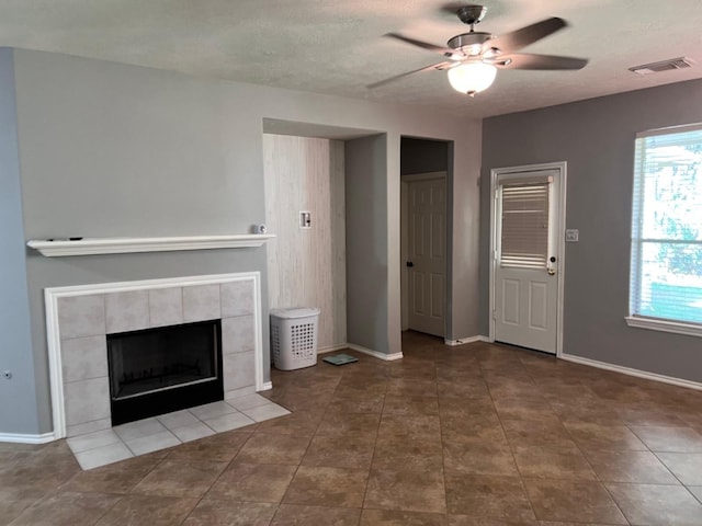 unfurnished living room with a textured ceiling, ceiling fan, and a fireplace