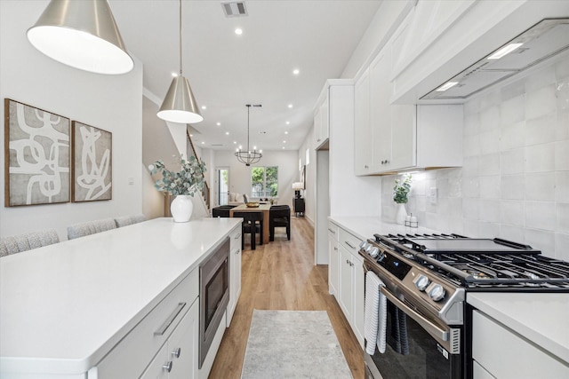 kitchen featuring ventilation hood, white cabinetry, stainless steel appliances, and hanging light fixtures