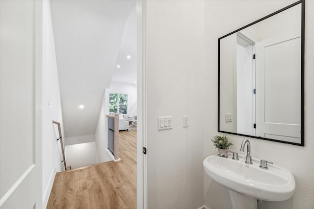 bathroom featuring sink, hardwood / wood-style floors, and vaulted ceiling