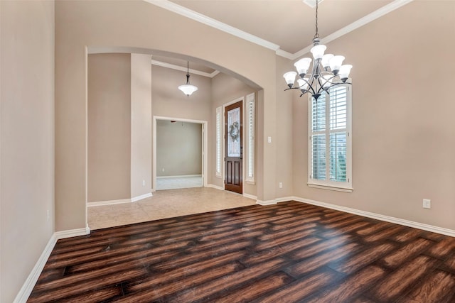 spare room featuring hardwood / wood-style floors, an inviting chandelier, and crown molding